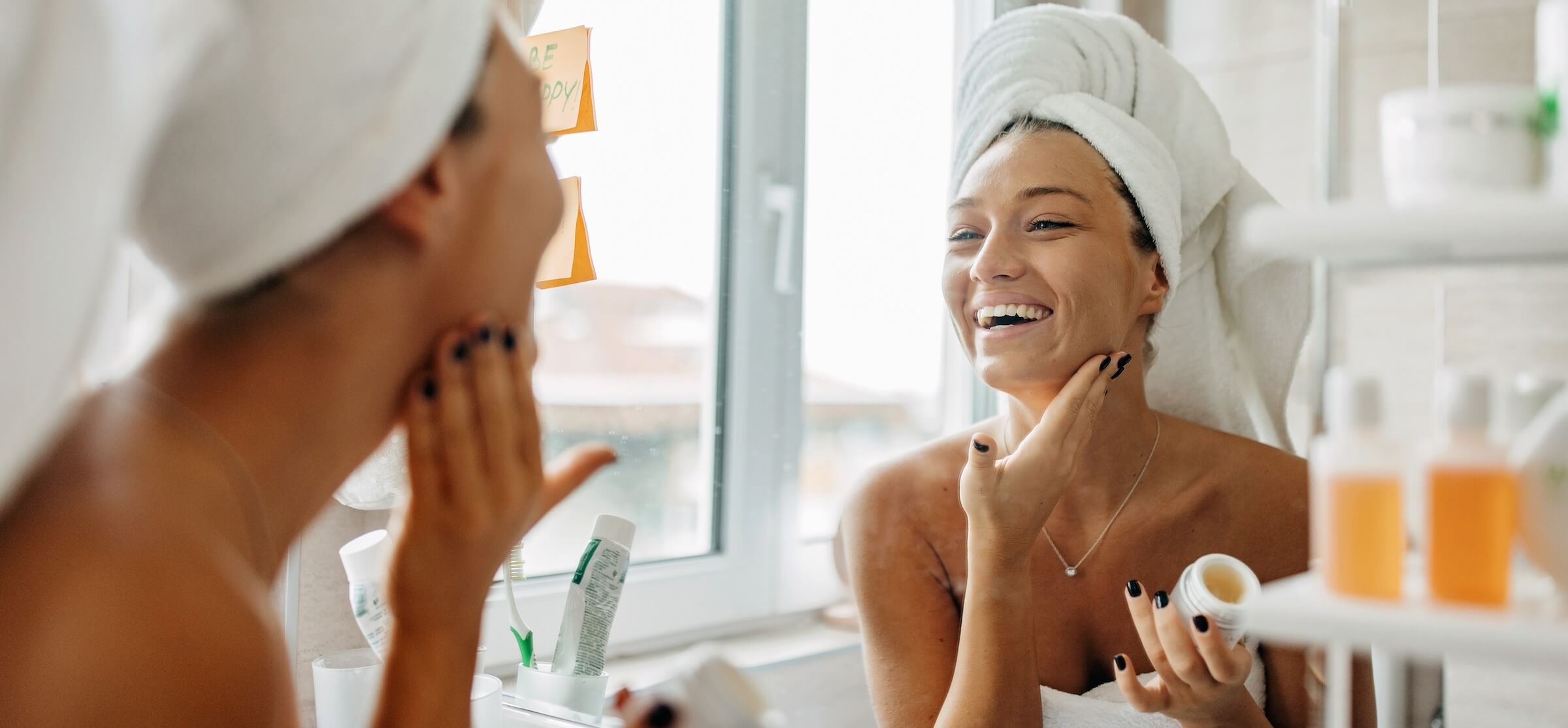 A woman applying lotion to her face.